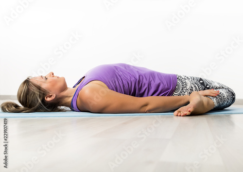 Beautiful fitness woman stretching legs doing pilates leg stretches exercises in gym