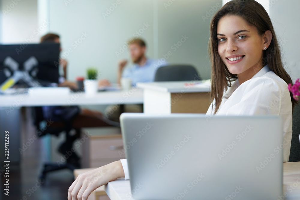 Beautiful business lady is looking at camera and smiling while working in office. Beautiful business lady is looking at camera and smiling while working in office.