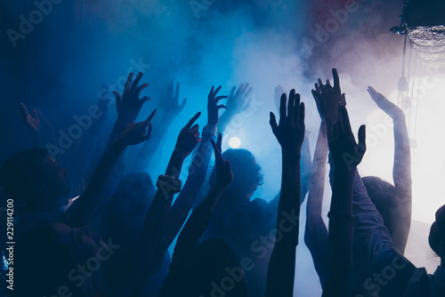 Close up cropped photo of people raised hands up in blue whire s