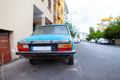 An old blue car stands on a street © filmbildfabrik