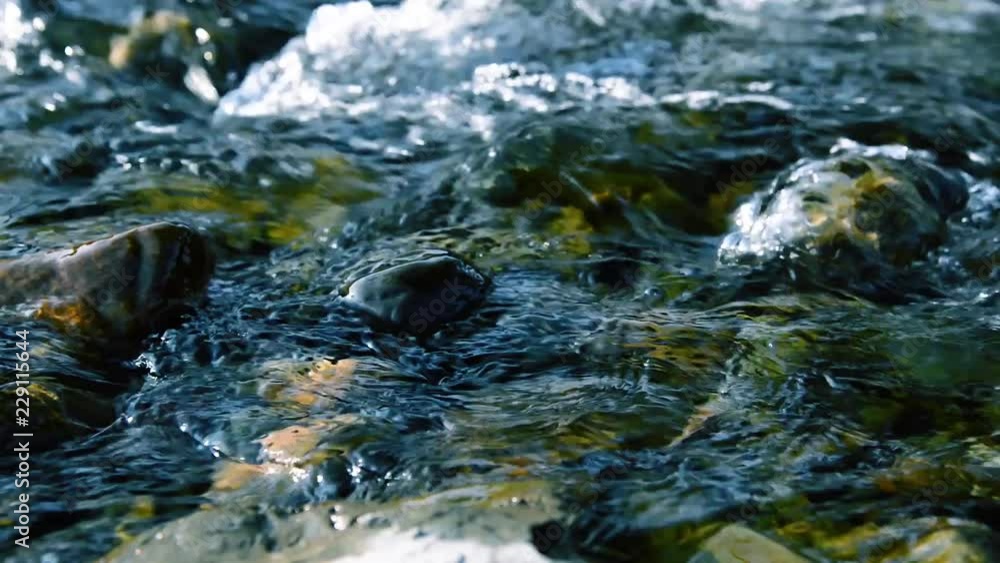 Motorised dolly slider shot of the splashing water in a small mountain river near forest. Huge wet rocks and sun rays. Horizontal steady movement at rural scene. Motorised dolly slider shot of the splashing water in a small mountain river near forest. Huge wet rocks and sun rays. Horizontal steady movement at rural scene.