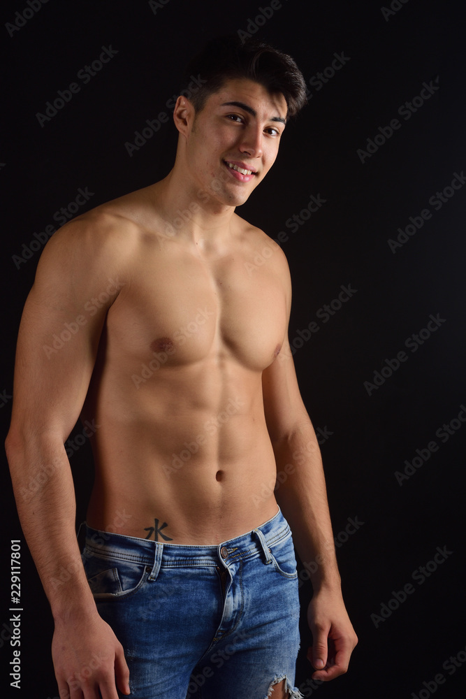Fototapeta premium portrait of young man with torso naked with jeans on black background
