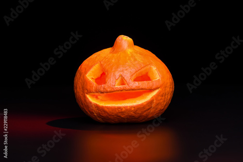 Halloween pumpkin lantern over black background with red backlig photo