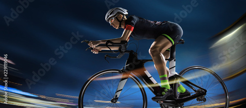 Sport background. Athletic woman cycling road bike in the evening. Dramatic view of the night city.