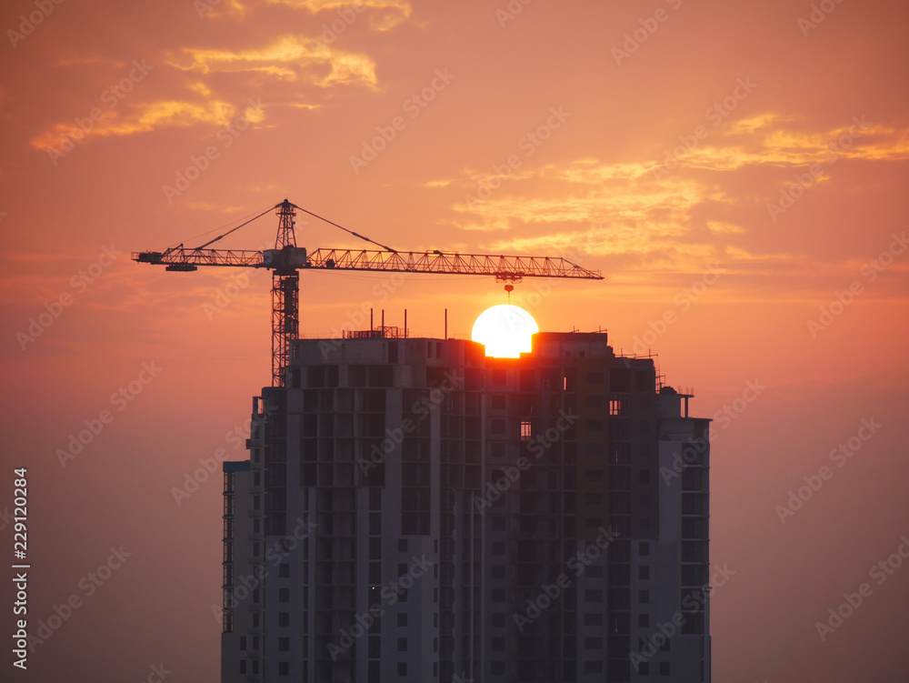 Silhouette of a building under construction against the rising sun. Construction site background. Silhouette of a building under construction against the rising sun. Construction site background.
