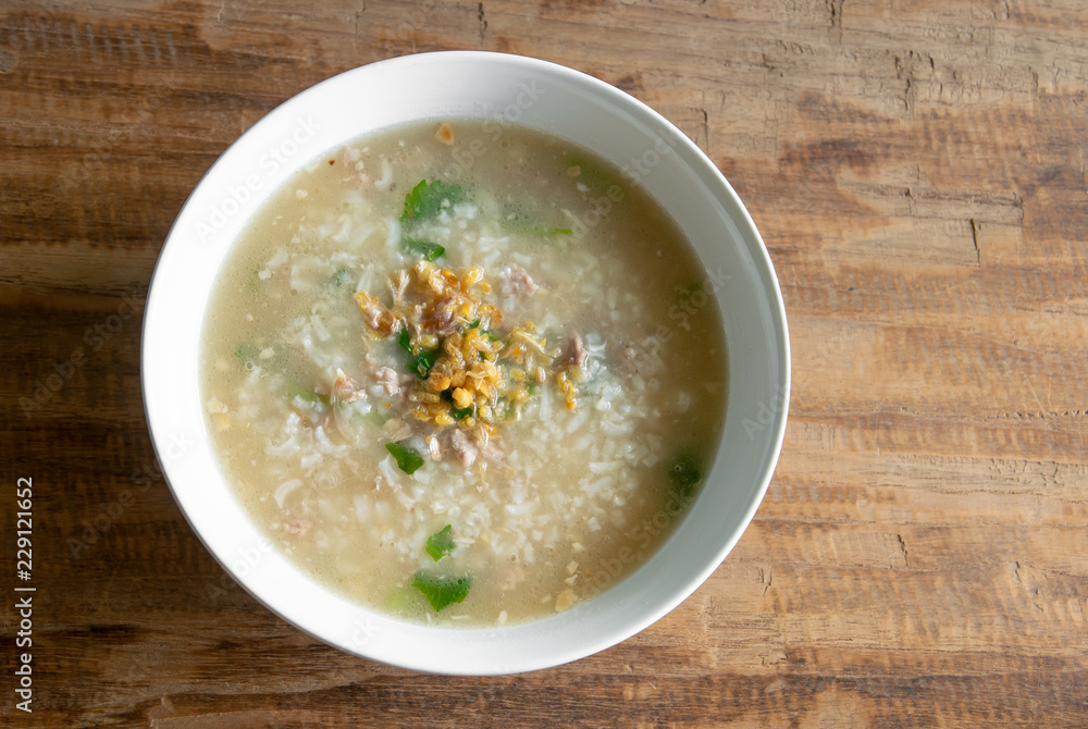 boiled rice in pork soup for a breakfast on wood background and space for text