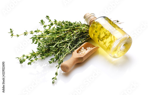 Bottle of essential oil with pills and thyme on white background photo