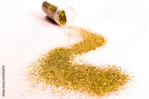 A track of scattered gold spangles on a pink background.