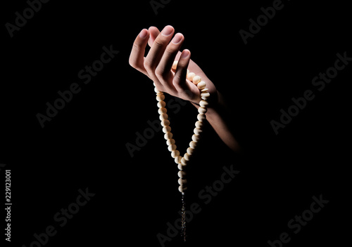 Man hands praying with prayer beads over dark background photo