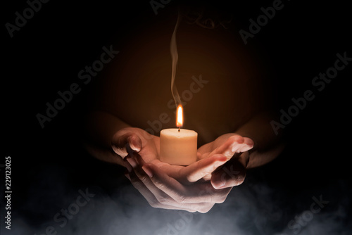 Fototapeta Hands holding candle over dark background