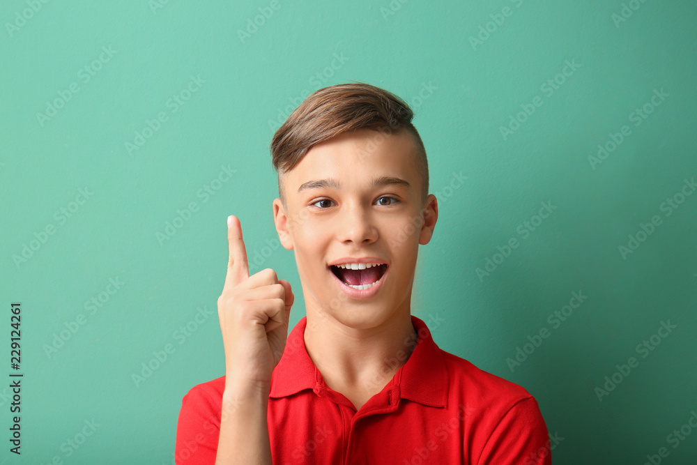Teenage boy with raised index finger on color background Teenage boy with raised index finger on color background