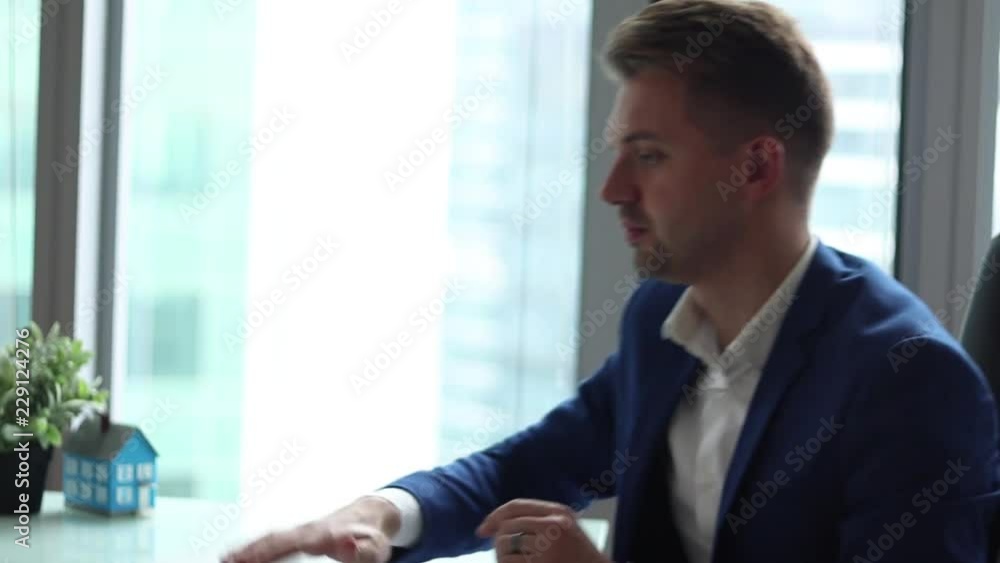 Young handsome businessman working on a computer while sitting in his office. Sharply closes the lid of the laptop. Young handsome businessman working on a computer while sitting in his office. Sharply closes the lid of the laptop.
