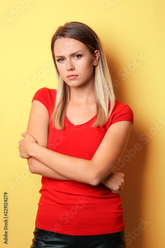 Beautiful frowning young woman on color background