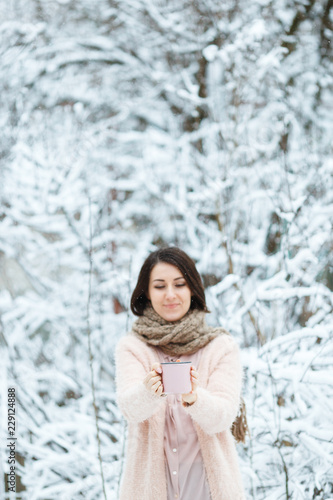 cute girl with a pink cup of coffee in the winter forest