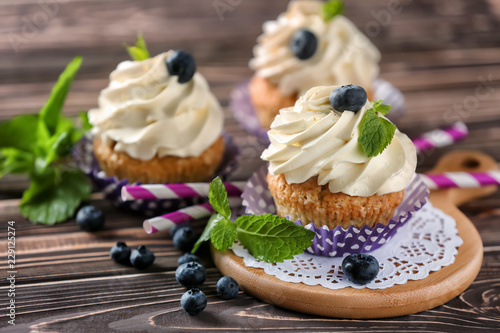 Delicious cupcakes with blueberries on wooden table