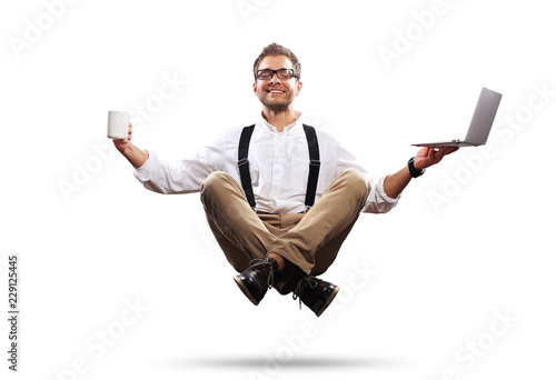 Fotografi Young man is soaring in the air with a Cup of coffee and a laptop