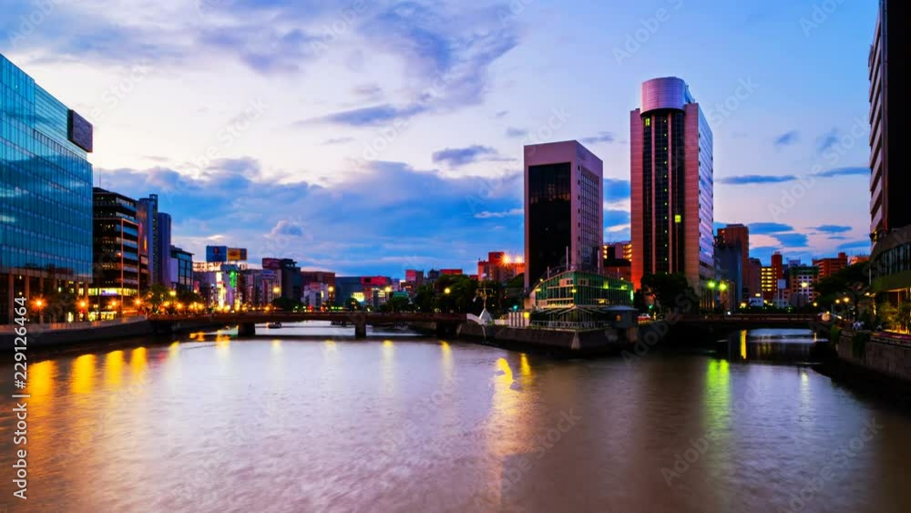 Fukuoka, Japan. A timelapse video of a sunrise in central Fukuoka, Japan, with a view of the Naka river, illuminated prominent skyscrapers and a clody colorful sky. Zoom in Fukuoka, Japan. A timelapse video of a sunrise in central Fukuoka, Japan, with a view of the Naka river, illuminated prominent skyscrapers and a clody colorful sky. Zoom in