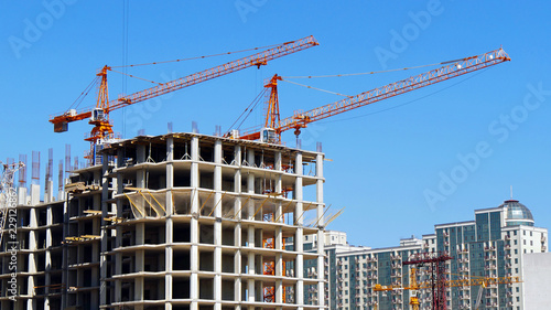 Two self-erection cranes near building. Construction site background.