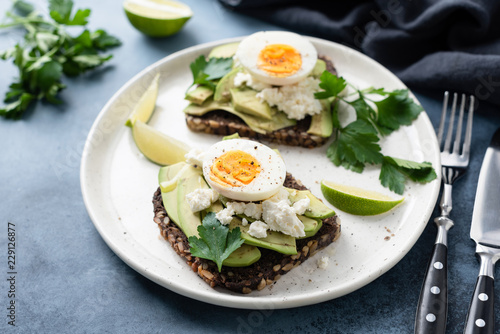 Healthy rye toast with avocado, egg, feta cheese on white plate. Healthy tasty breakfast, lunch or snack