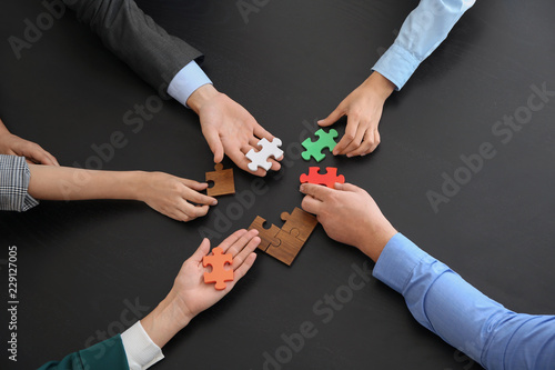 Business team assembling puzzle on dark table photo