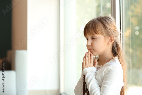 Little girl praying near wi...