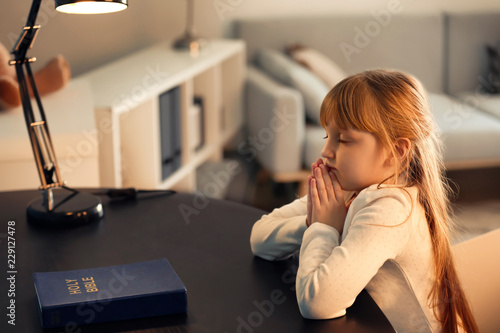 Φωτογραφία Little girl praying at dark table
