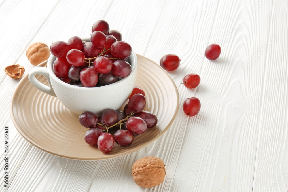Cup with sweet grapes on white wooden table Cup with sweet grapes on white wooden table