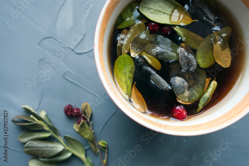 Natural Tea with lingonberry and leaves close-up on a gray background