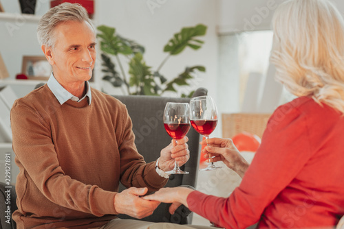 Love and support. Portrait of loving happy elderly husband and wife drinking wine and looking at each other while holding hands and having romantic dinner