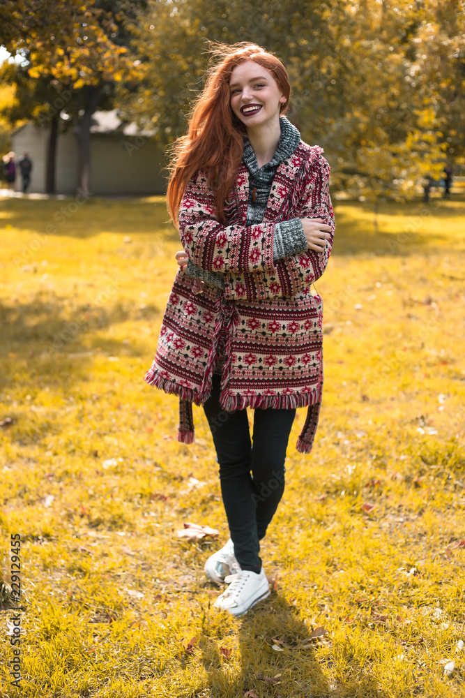 Redhead young laughing happy woman with freckles and dark lipstick posing outdoors in park. Looking camera. Redhead young laughing happy woman with freckles and dark lipstick posing outdoors in park. Looking camera.