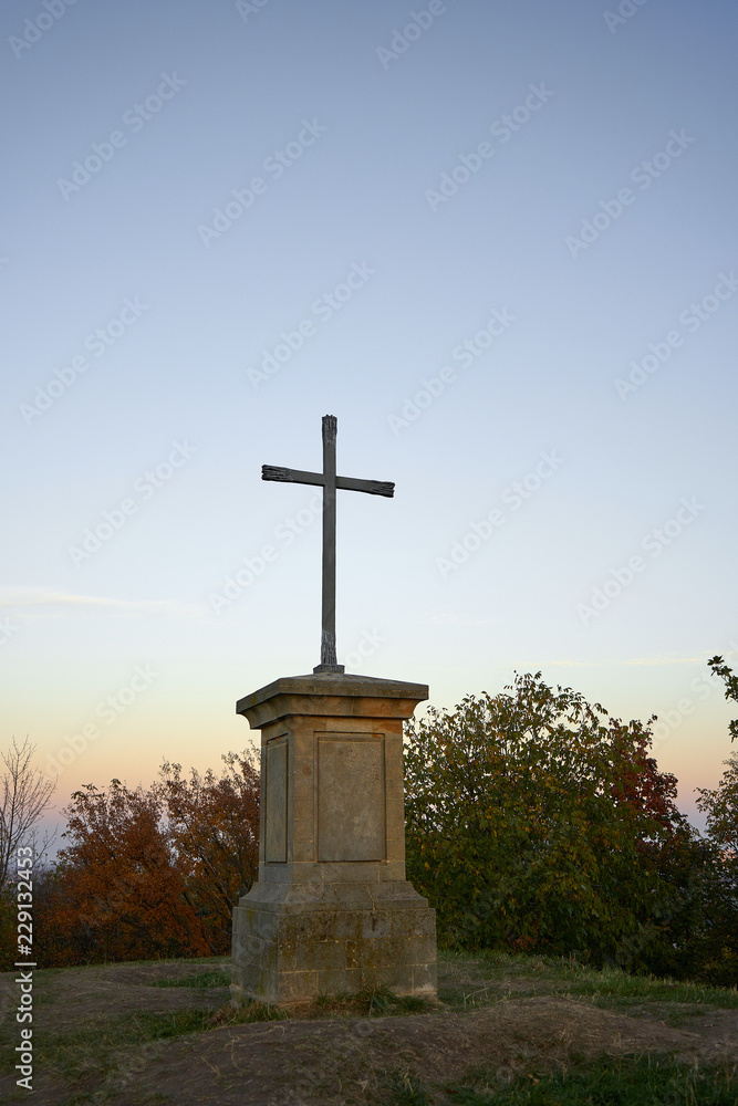 Metal cross on the top of the hill at sunset