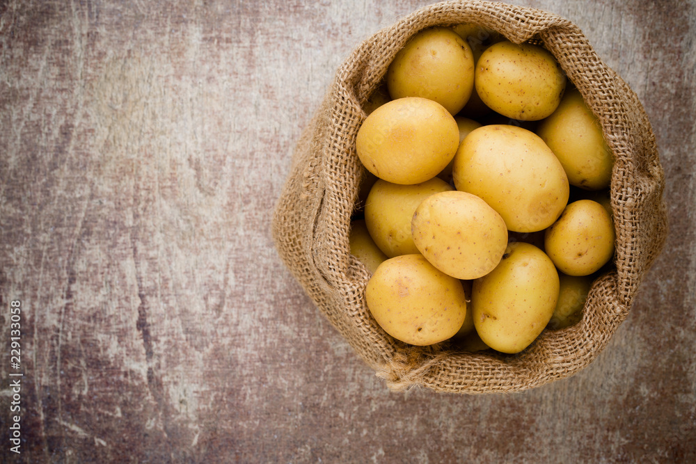 Sack of fresh raw potatoes on wooden background, top view. Sack of fresh raw potatoes on wooden background, top view.