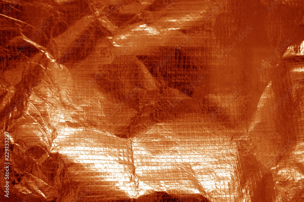 Crumpled plastic textile texture in orange color.