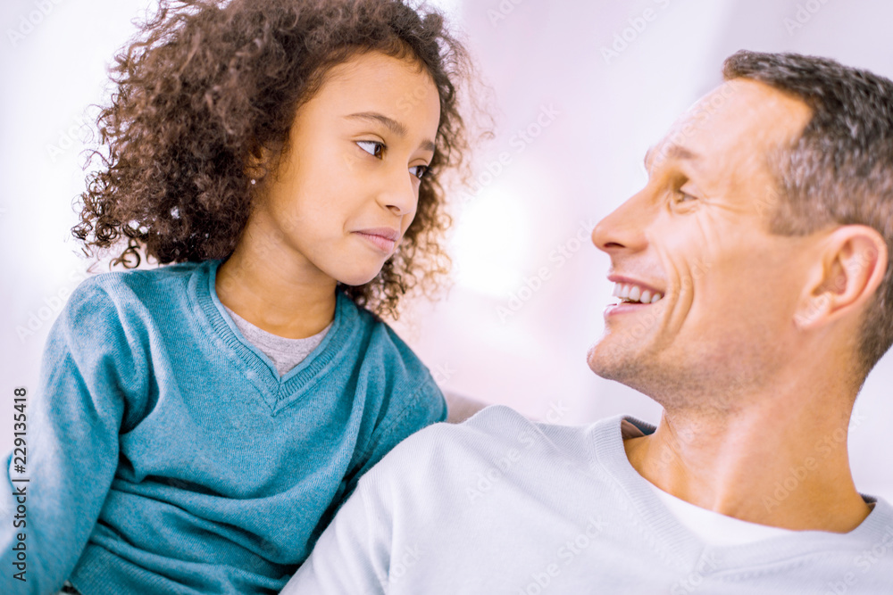Fototapeta premium Lets joke. Emotional child looking at her dad while being at home together