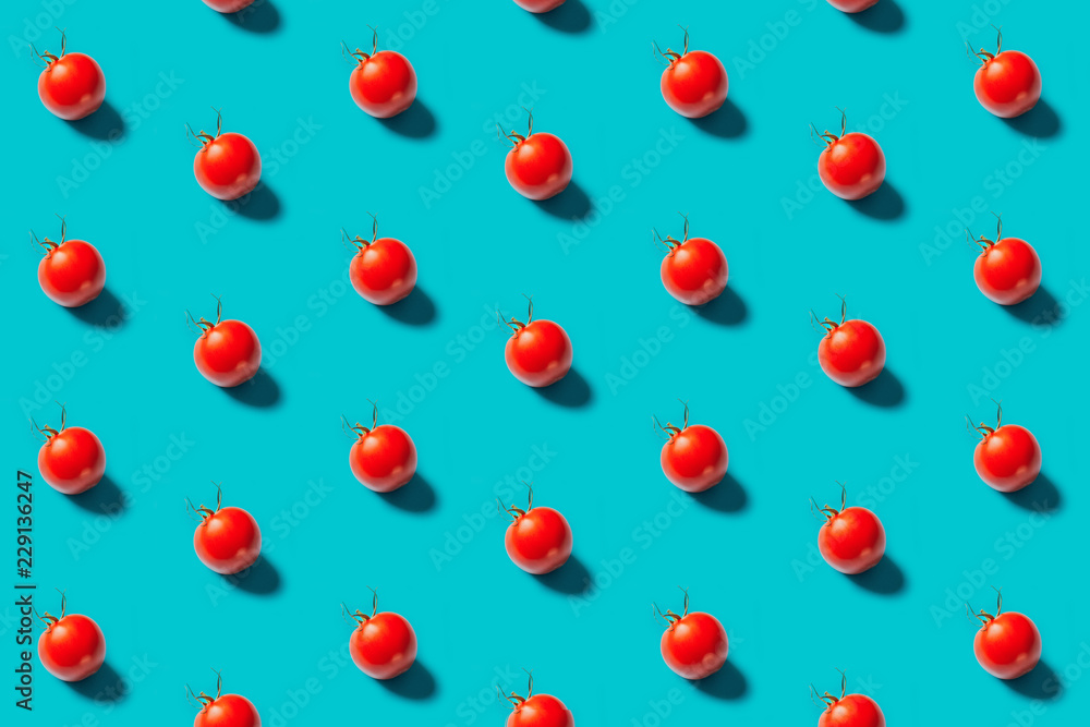 Red tomatoes pattern on a blue background, flat lay. Top view. Red tomatoes pattern on a blue background, flat lay. Top view.