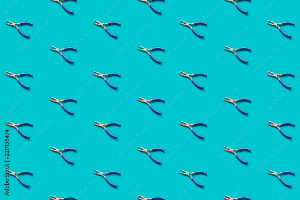 Pliers with blue handles pattern on a green background, flat lay. Pop view Pliers with blue handles pattern on a green background, flat lay. Pop view