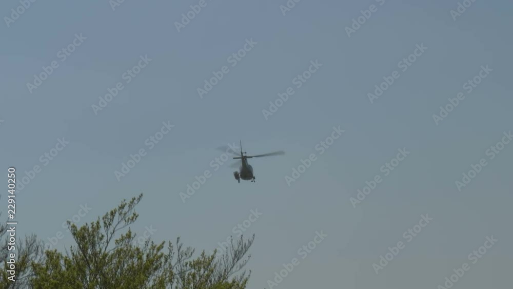 A rescue helicopter with stretcher flying in a cloudy sky A rescue helicopter with stretcher flying in a cloudy sky