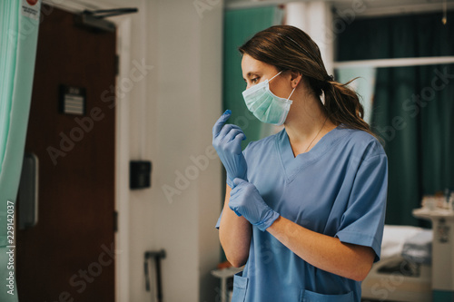 Female nurse with a mask putting on gloves photo