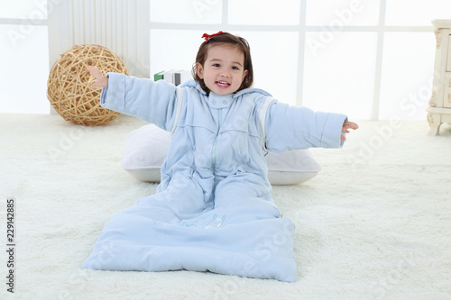 A little girl was sitting on the bed in her sleeping bag