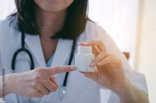 young female doctor or pharmacist with stethoscope holding or showing bottle of pills in hand in hospital or clinic  health care  medical  medicine  pharmacy and insurance concept