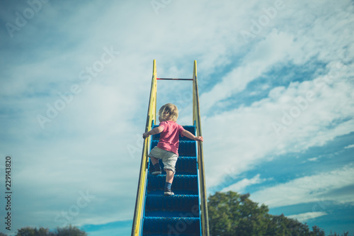 Toddler climbing up a slide photo