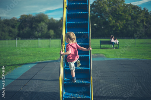 Toddler climbing up a slide photo