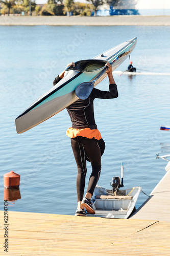 Young athlete guy carries a kayak.