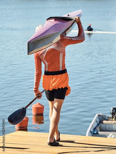 Young athlete guy carries a kayak.