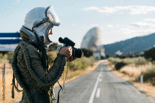 Beautiful woman using old camera dressed as an astronaut. photo