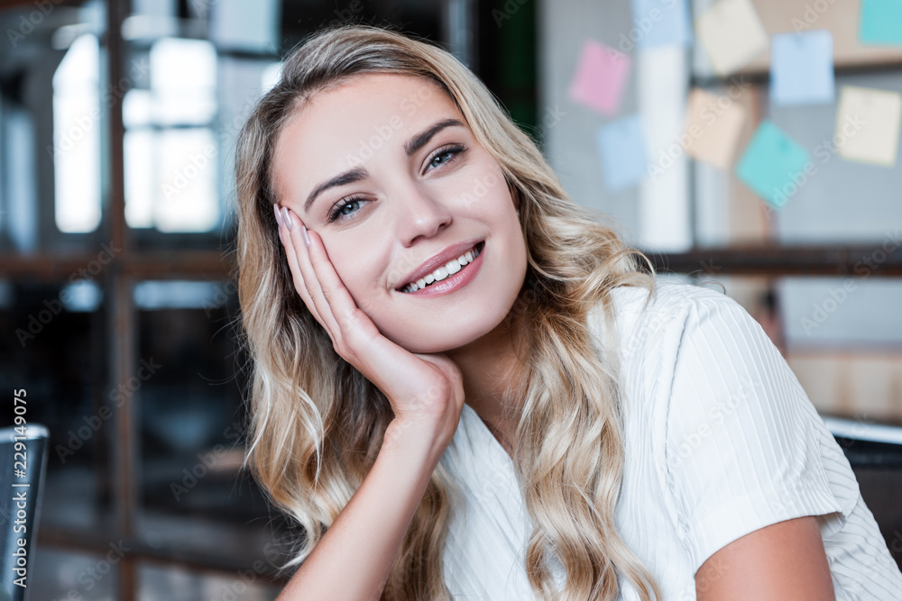 portrait of beautiful young blonde businesswoman smiling at camera in office