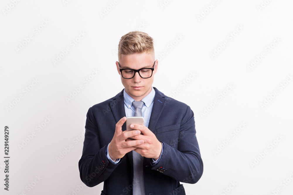 Portrait of a young man with smartphone in a studio, text messaging.