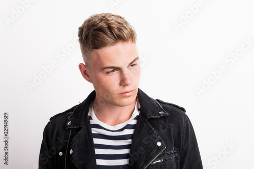 A confident young man in a studio, wearing striped T-shirt.