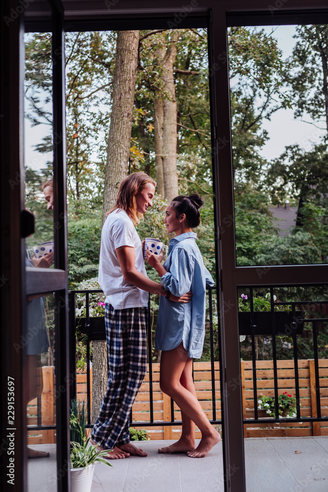 So romantic. Positive nice couple drinking tea while standing together on the balcony So romantic. Positive nice couple drinking tea while standing together on the balcony