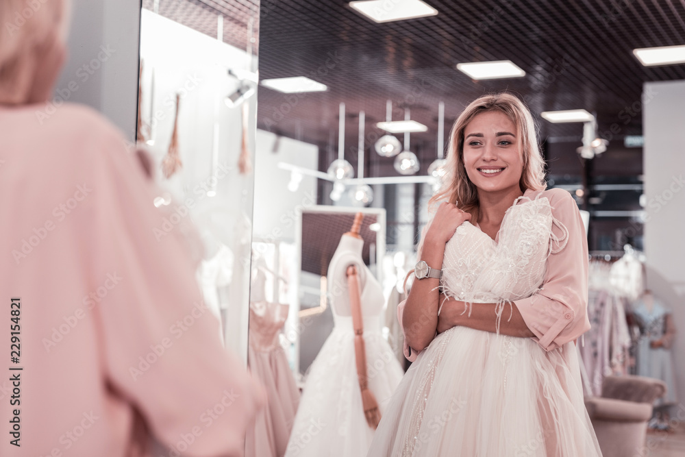Perfect bride. Nice young woman smiling while looking at her reflection in the mirror